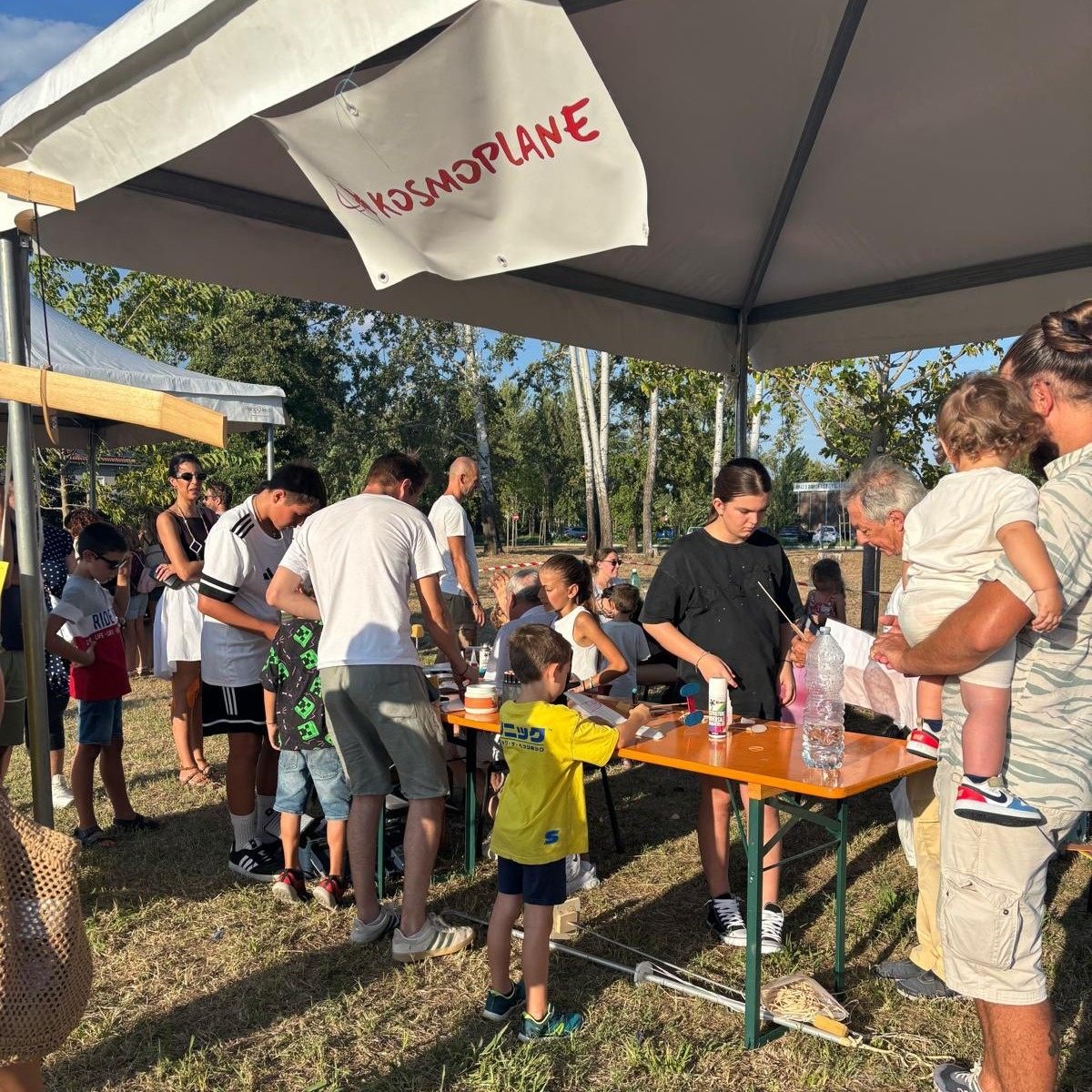 Bambini e genitori costruiscono aeromodelli sotto il gazebo